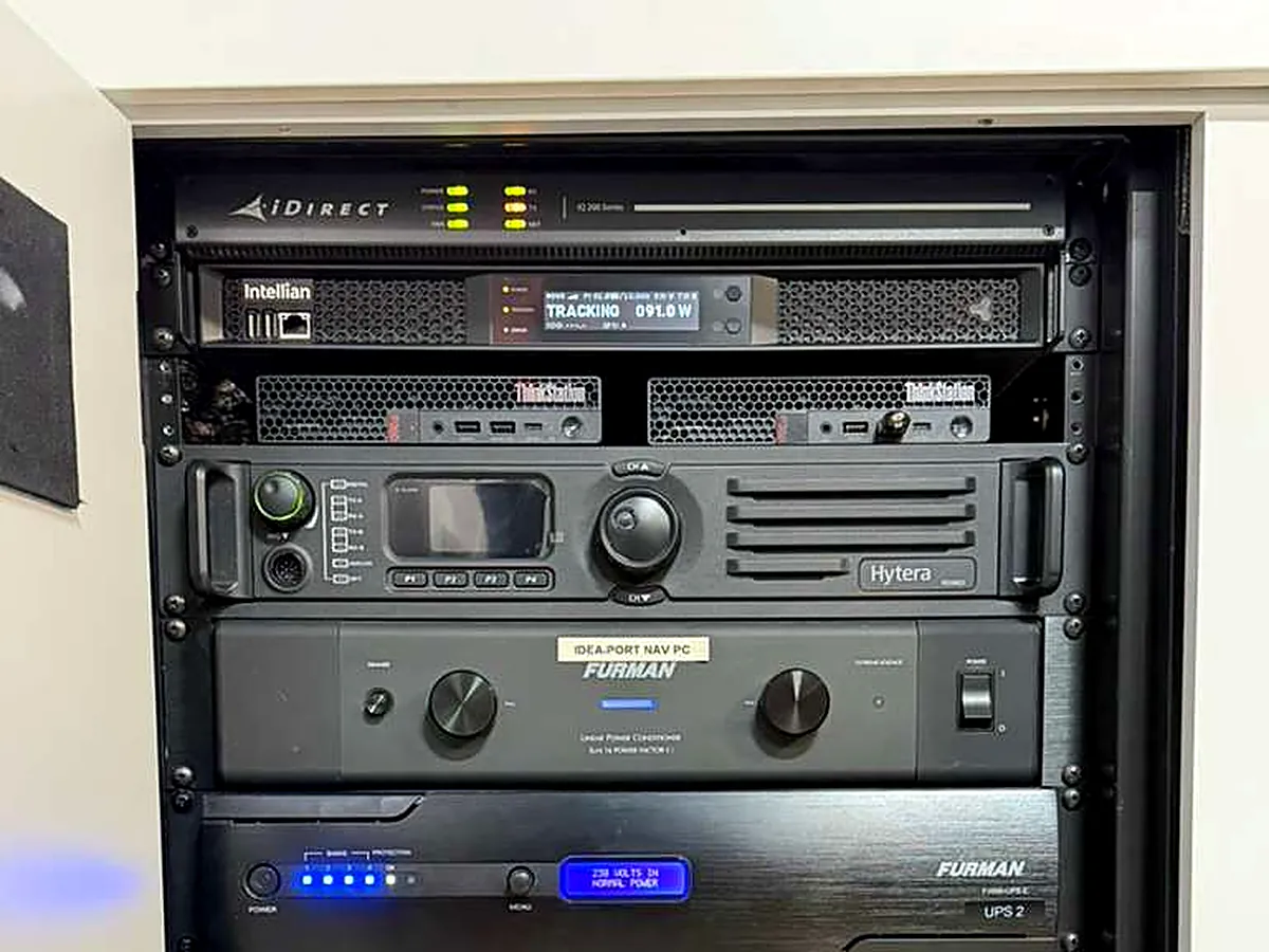 Marine-grade satellite communications and control rack aboard a yacht — iDirect satellite modem, Intellian antenna control, and Hytera radio, professionally wired