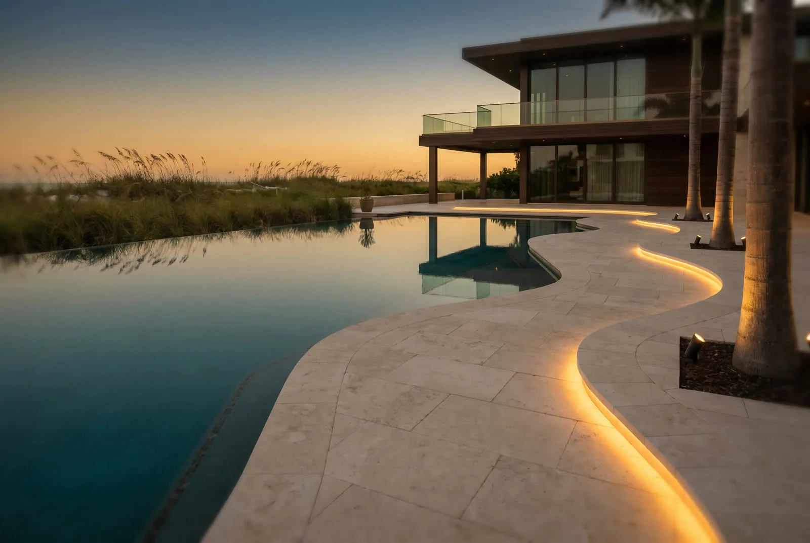 Luxury infinity pool deck with integrated pathway lighting at twilight